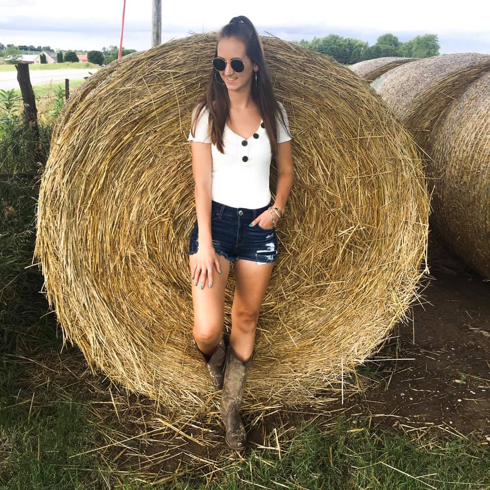 round sunglasses, cowgirl boots, hay bale