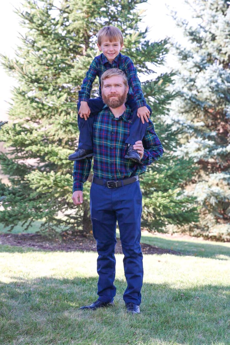 A son sitting on top of dad's shoulders smiling