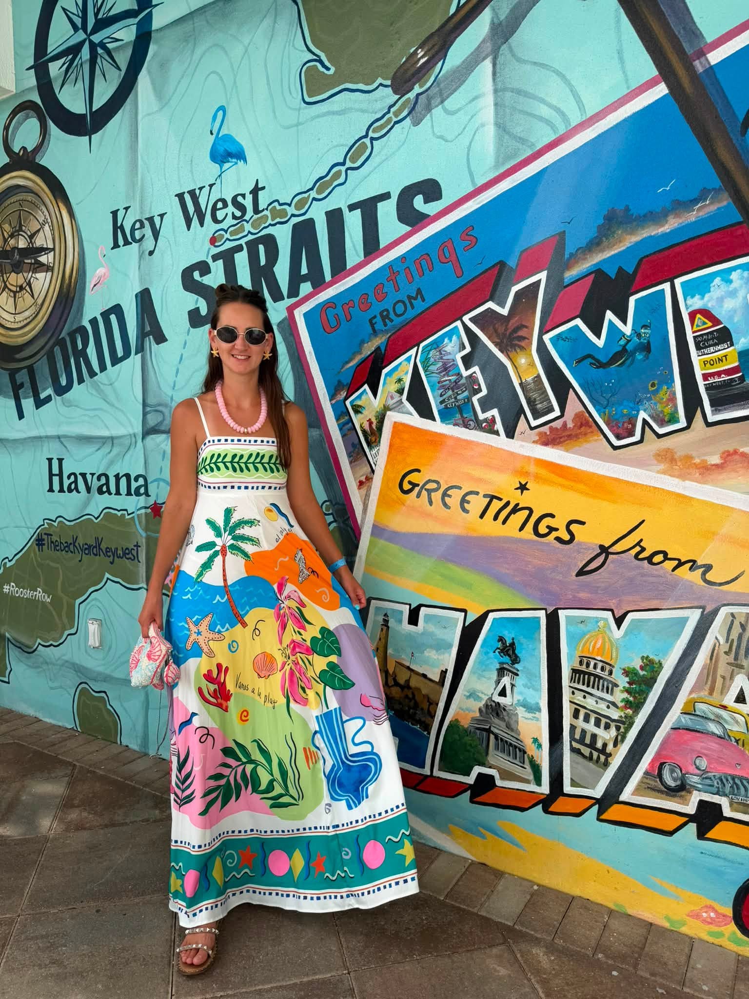 woman wearing tropical print maxi dress in front of mural