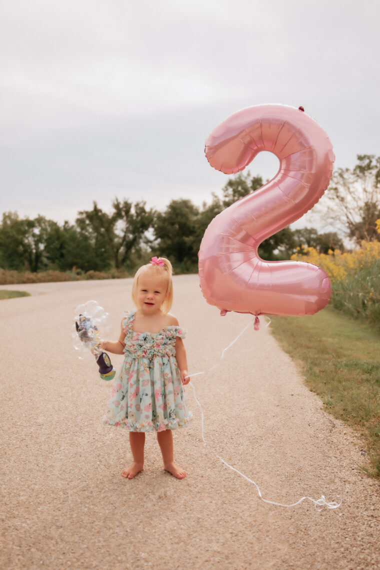 toddler girl holding #2 birthday balloon